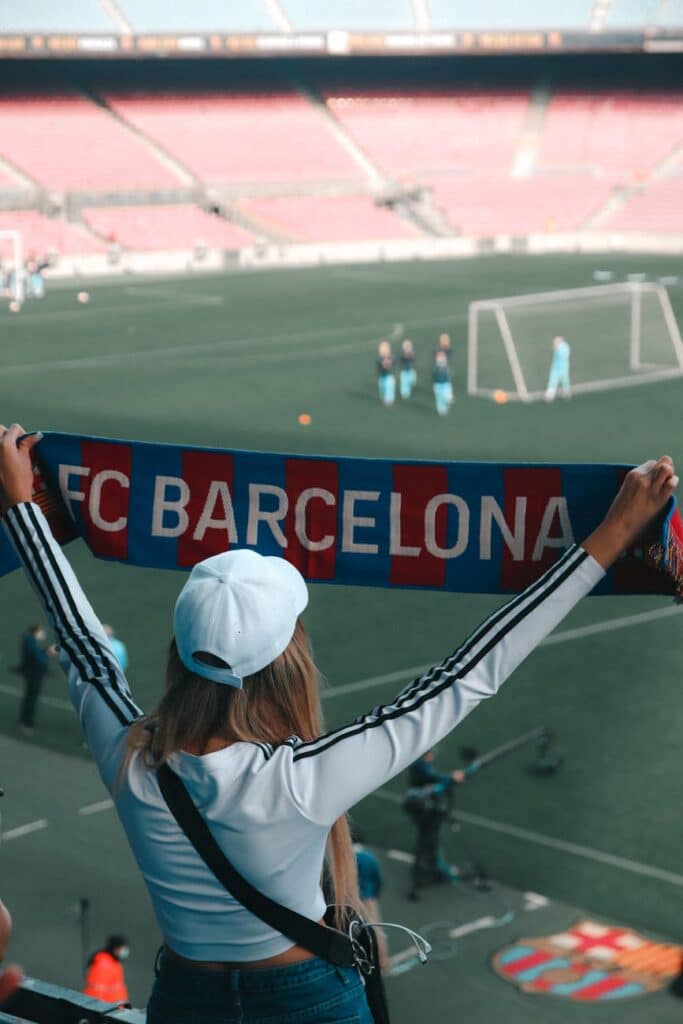 woman watching football match holding barcelona scarf