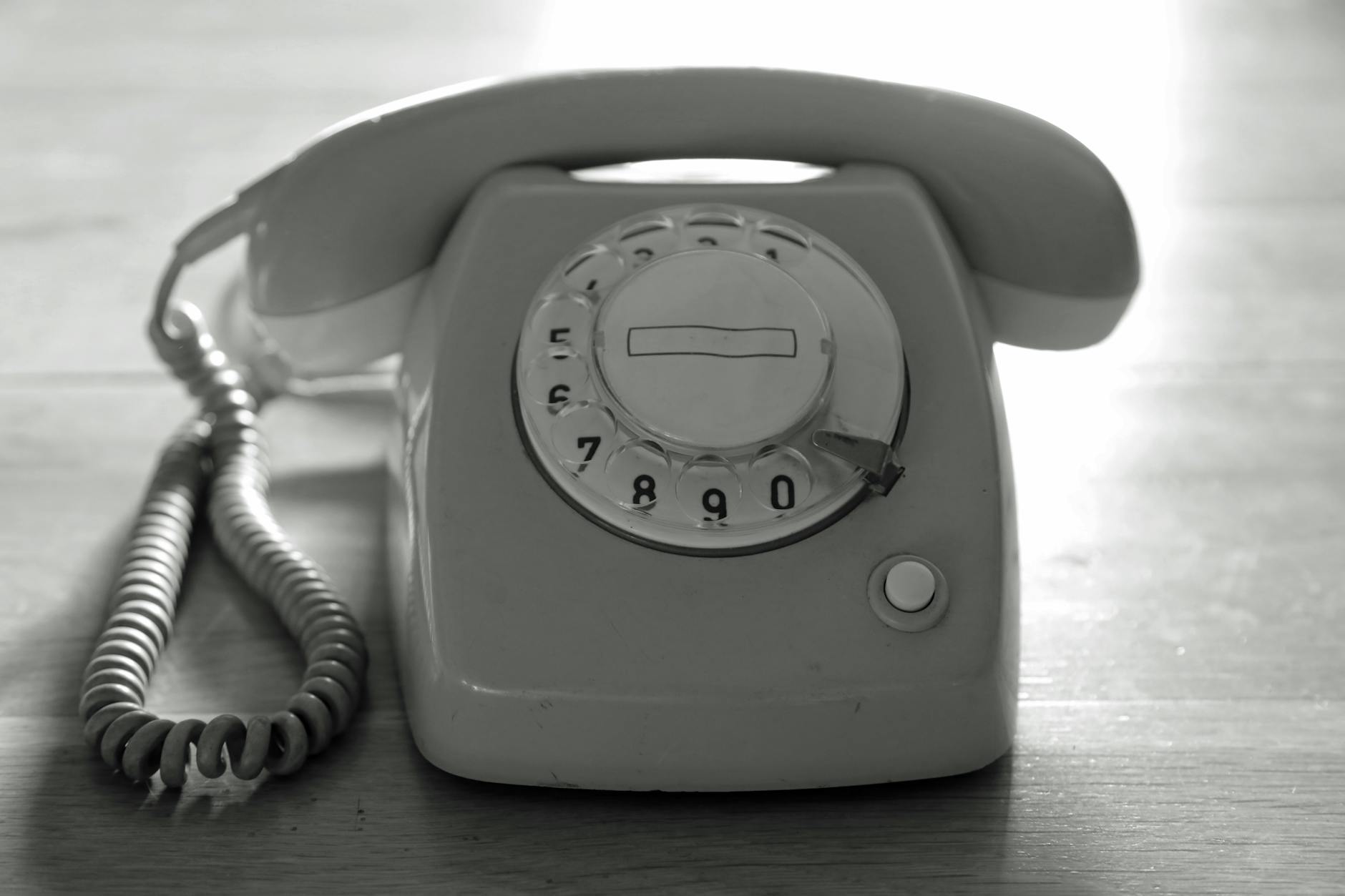 vintage black and white rotary phone on a wooden surface